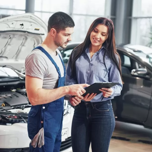 man mechanic woman customer discussing repairs done her vehicle