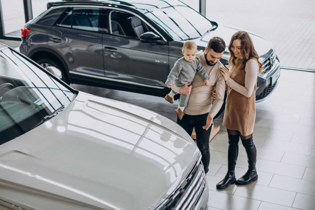 family with toddler girl choosing car car showroom
